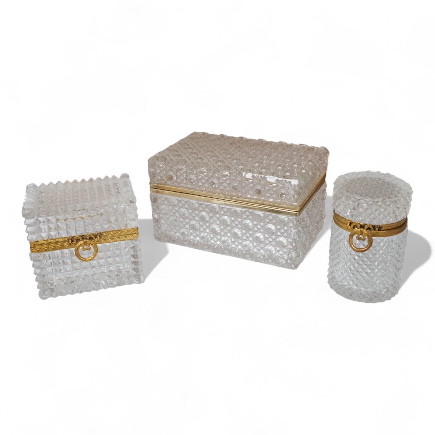 A deeply cut rectangular glass casket, a similar smaller casket and a cylindrical container, all with gilt metal mounts, largest 18cm wide x 10.5cm high.